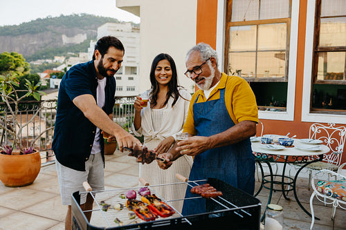 Family enjoying a traditional Brazilian barbecue on a sunny rooftop setting