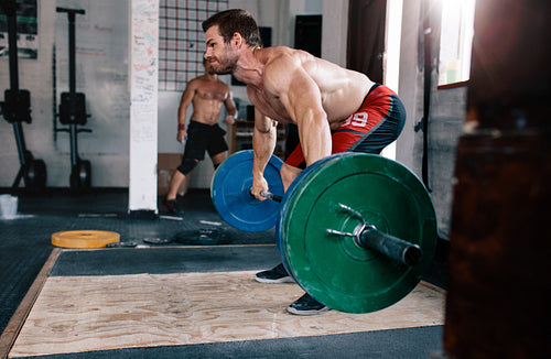 Strong young man exercising with heavy weights at gym