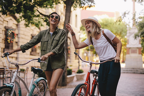 Women walking down the city street with their bicycles