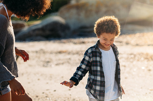 Kid walking on beach with his mother