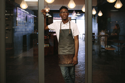 Young entrepreneur standing in front of his coffee shop
