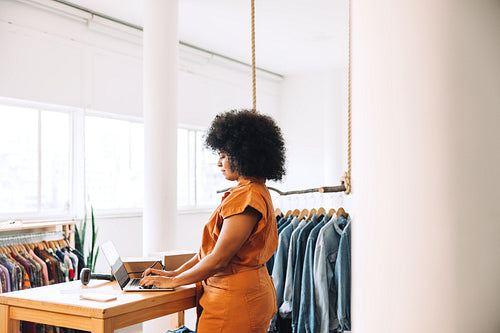 Female business owner using a laptop in her clothing store