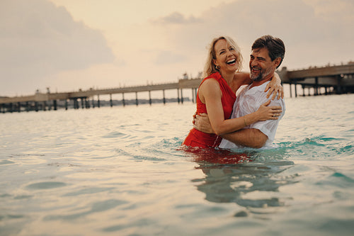Retired couple enjoying playful moments and joy at sunset by the ocean