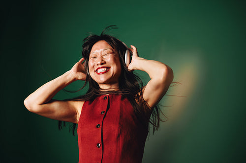 Joyful woman immersed in music wearing headphones in studio portrait