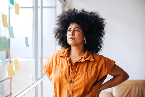 Pensive young businesswoman standing next to a glass wall