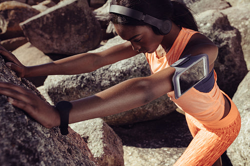 Strong woman stretching against a rock
