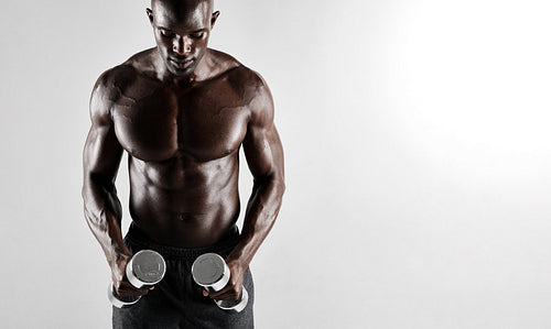 Muscular african man exercising with dumbbells