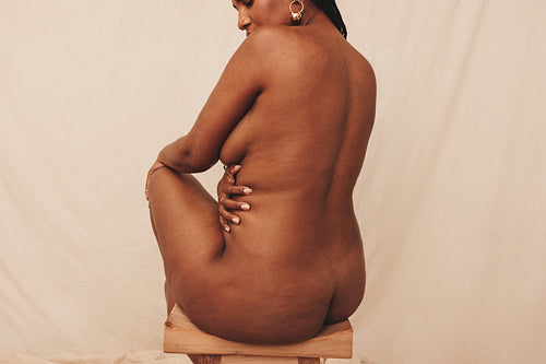 Woman embracing her nude body in a studio
