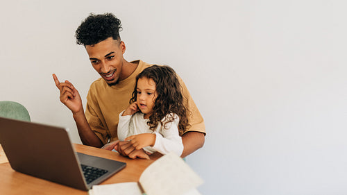 Young dad watching an online educational video with his daughter
