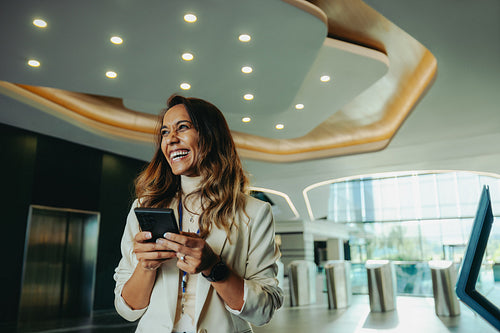 Smiling Indian businesswoman holding a smartphone in a modern office
