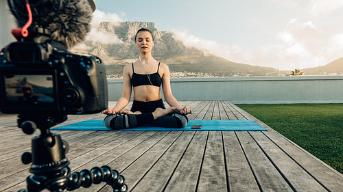 Female blogger recording yoga content on camera outdoors