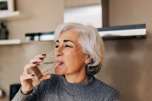 Mature woman drinking fresh clean water at home