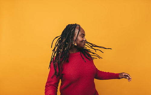 Joyful black woman whipping her dreadlocks in a studio