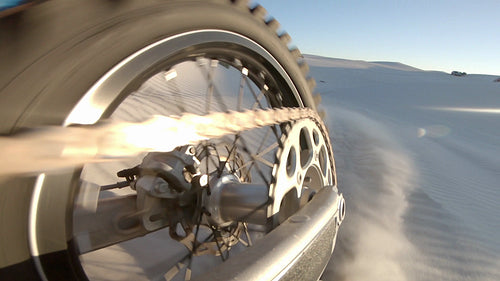 Motorbike wheels creating dust on sand dunes