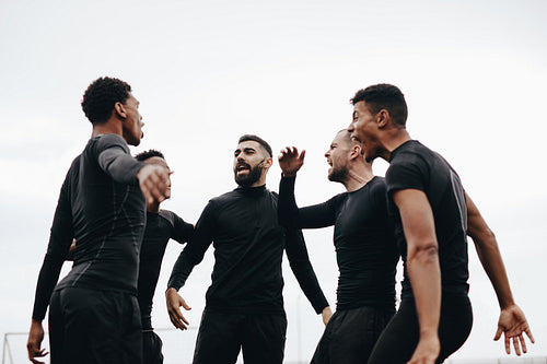 Football players standing on field and shouting in joy
