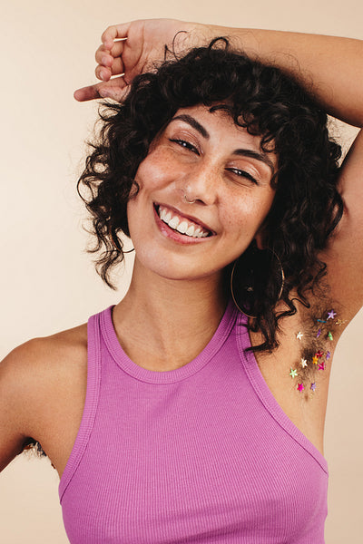 Happy young woman showing her confetti-decorated underarm hair