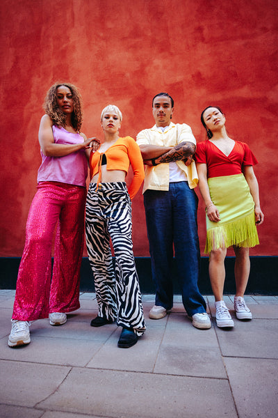 Friends pose together outdoors against a bold urban wall