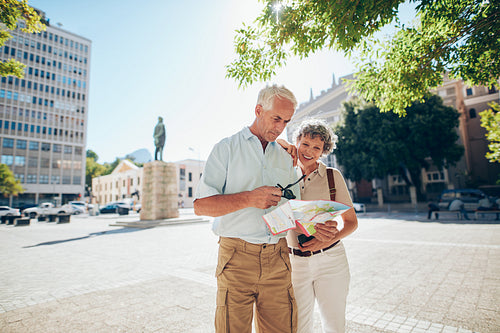 Senior couple using a city map for location in the town
