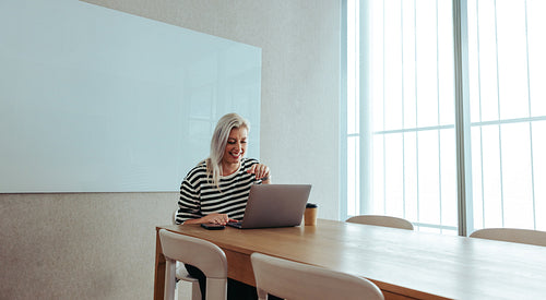 Caucasian female entrepreneur working on a laptop with a big smile