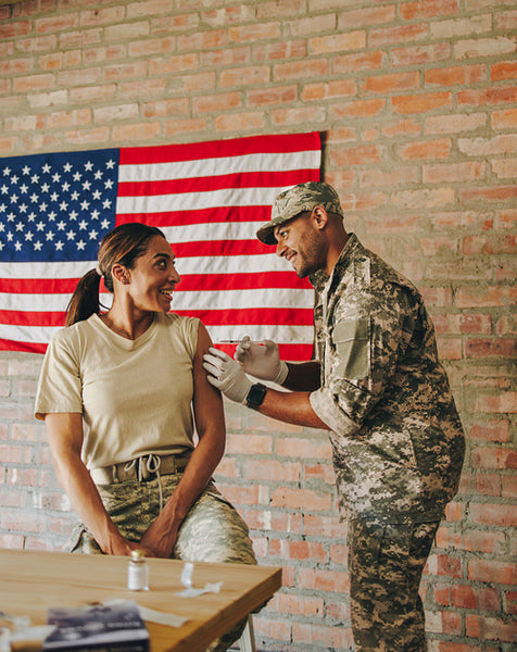 Smiling military doctor vaccinating a female soldier in the army