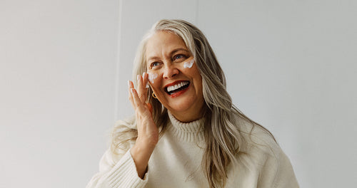 Skincare woman applies facial cream in the studio
