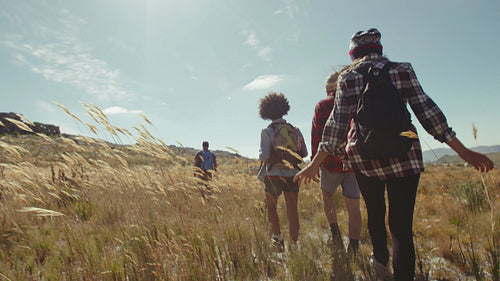 Young people walking through grassy fields in countryside