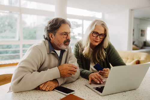 Senior woman shops with partner on laptop at home