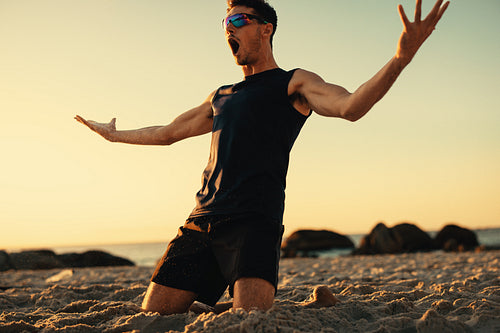 Victorious athlete celebrating championship win on the beach at sunset