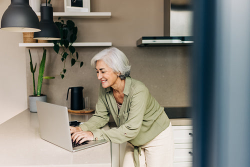 Happy senior woman working on her laptop at home