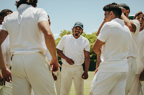 Cricket team celebrating victory with a cheerful team huddle outside