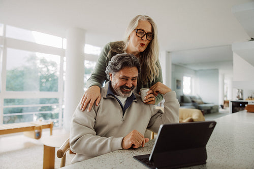 Senior couple share family contact on a tablet at home