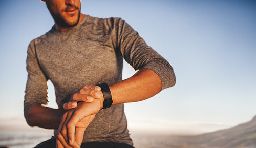 Young runner checking the time on his wristwatch