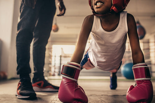 Boxing kid training inside a boxing gym with his coach