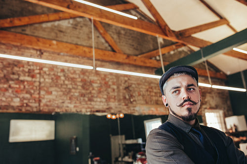 Young man with cap standing in barber shop