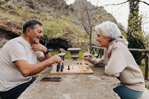 Retired senior couple playing chess together outdoors
