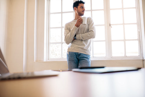Man standing in office drinking coffee