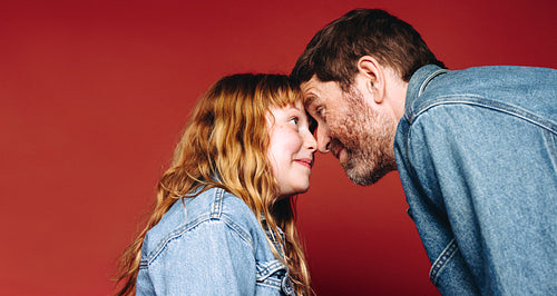 Father and daughter share a tender eye contact moment with foreheads touching