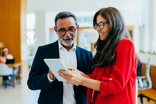 Mature businessman and female executive using a tablet in a bright office