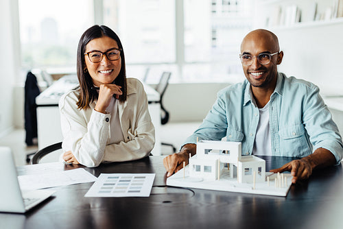 Two architects working with a 3D house model in an office