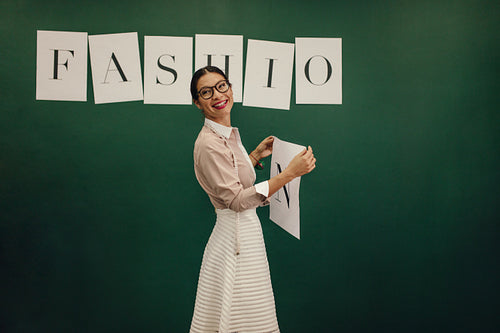 Female designer standing near wall with sticker