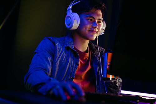 Computer gamer holding an energy drink as he plays a video game on a pc