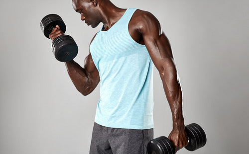 Fit young black man exercising with dumbbells