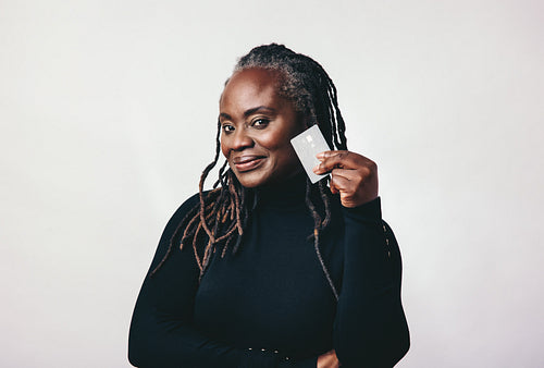 Mature woman looking at the camera while holding a credit card