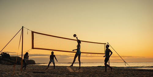 Athletes enjoying a coastal beach volleyball championship at sunset