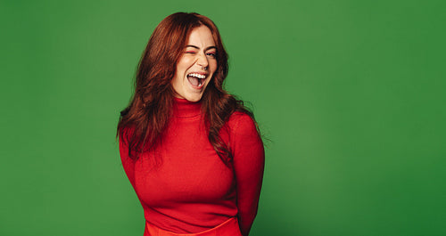 Joyful woman with sweater and nose ring standing on vibrant green background