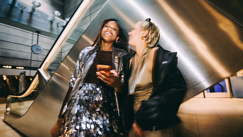 Women laugh together at a metro station on a night out