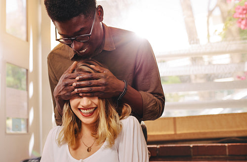 Man surprising girlfriend at coffee shop