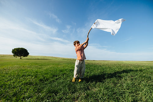 Child waving white flag symbolizing peace and hope