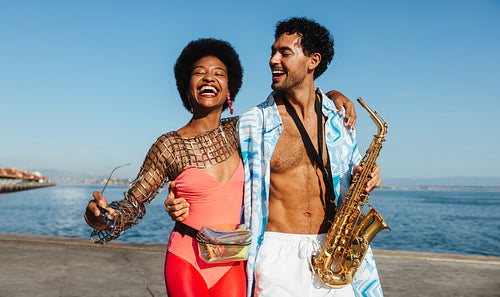 Happy couple by the sea with saxophone