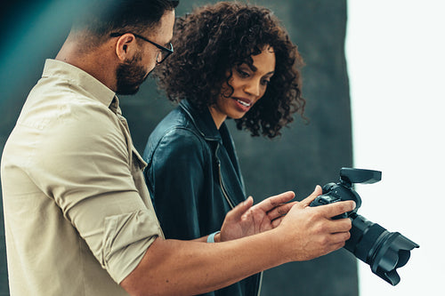Side view of a photographer showing image in his camera to a model
